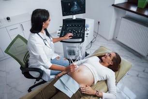 여성 의사는 병원에서 임산부를 위해 초음파 검사를합니다.