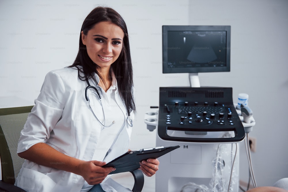 Portrait of obstetric doctor that sits in the clinic room with ultrasound device.