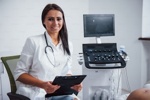 Porträt eines geburtshilflichen Arztes, der mit Ultraschallgerät im Klinikzimmer sitzt.