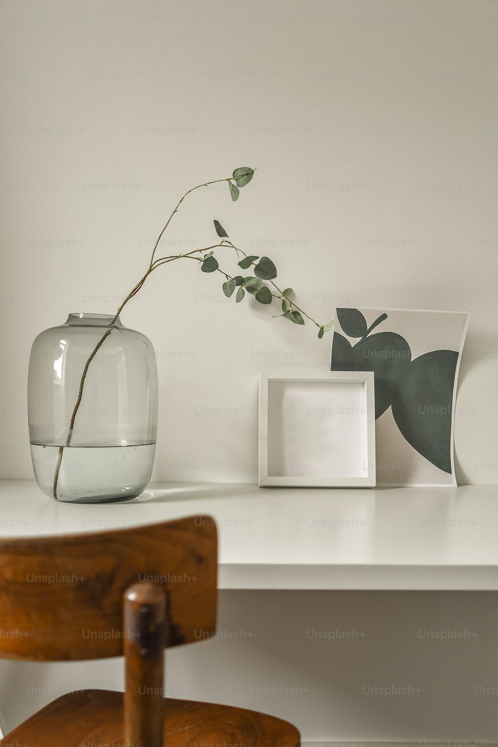 Einfacher minimalistischer Schreibtisch mit dekorativer Pflanze in einem Glasgefäß. Kleiner Arbeitsplatz in einem modernen Haus
