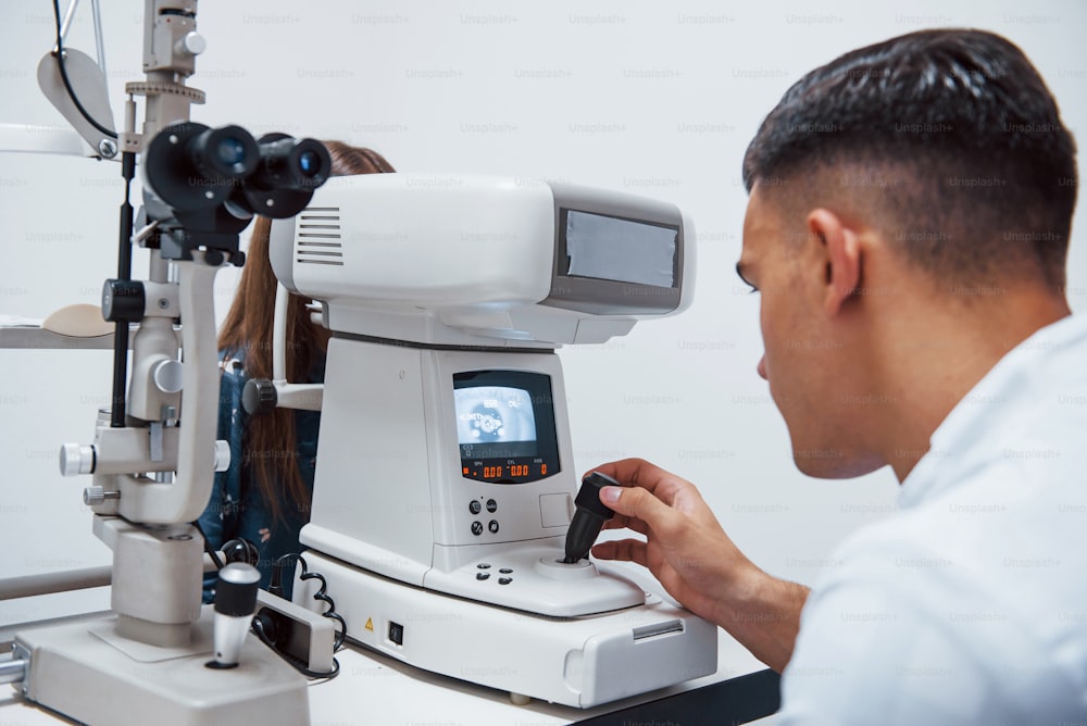 Oculist testa la vista del paziente utilizzando una speciale macchina moderna.