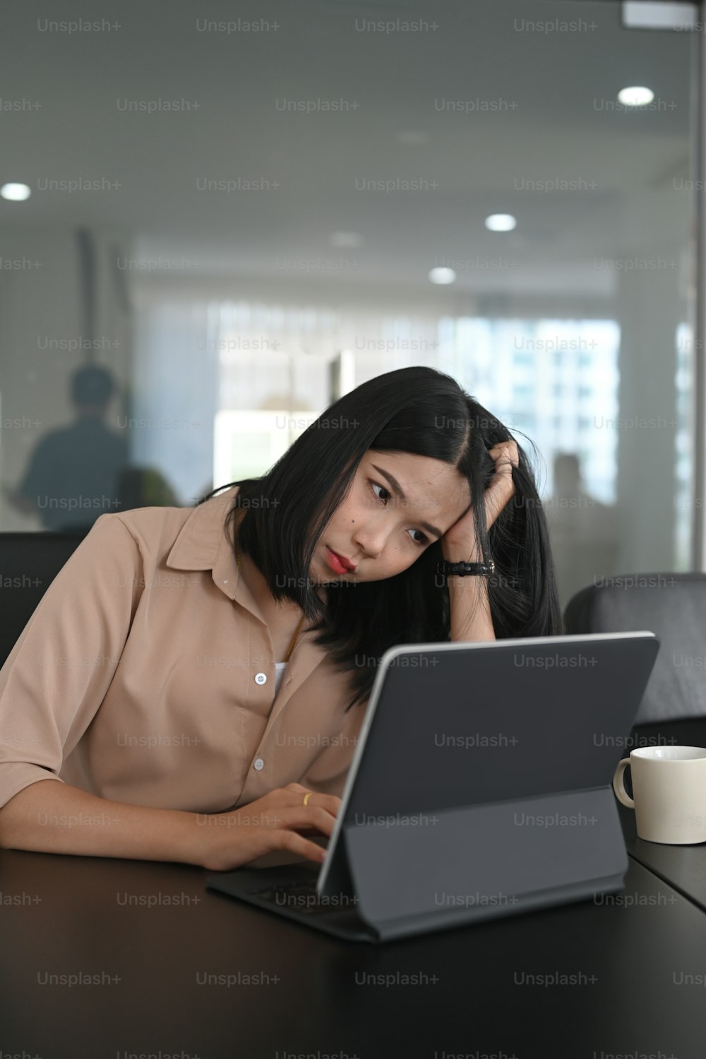 Junge Geschäftsfrau sitzt mit Computer-Tablet am Schreibtisch und leidet unter Stress bei der Arbeit.