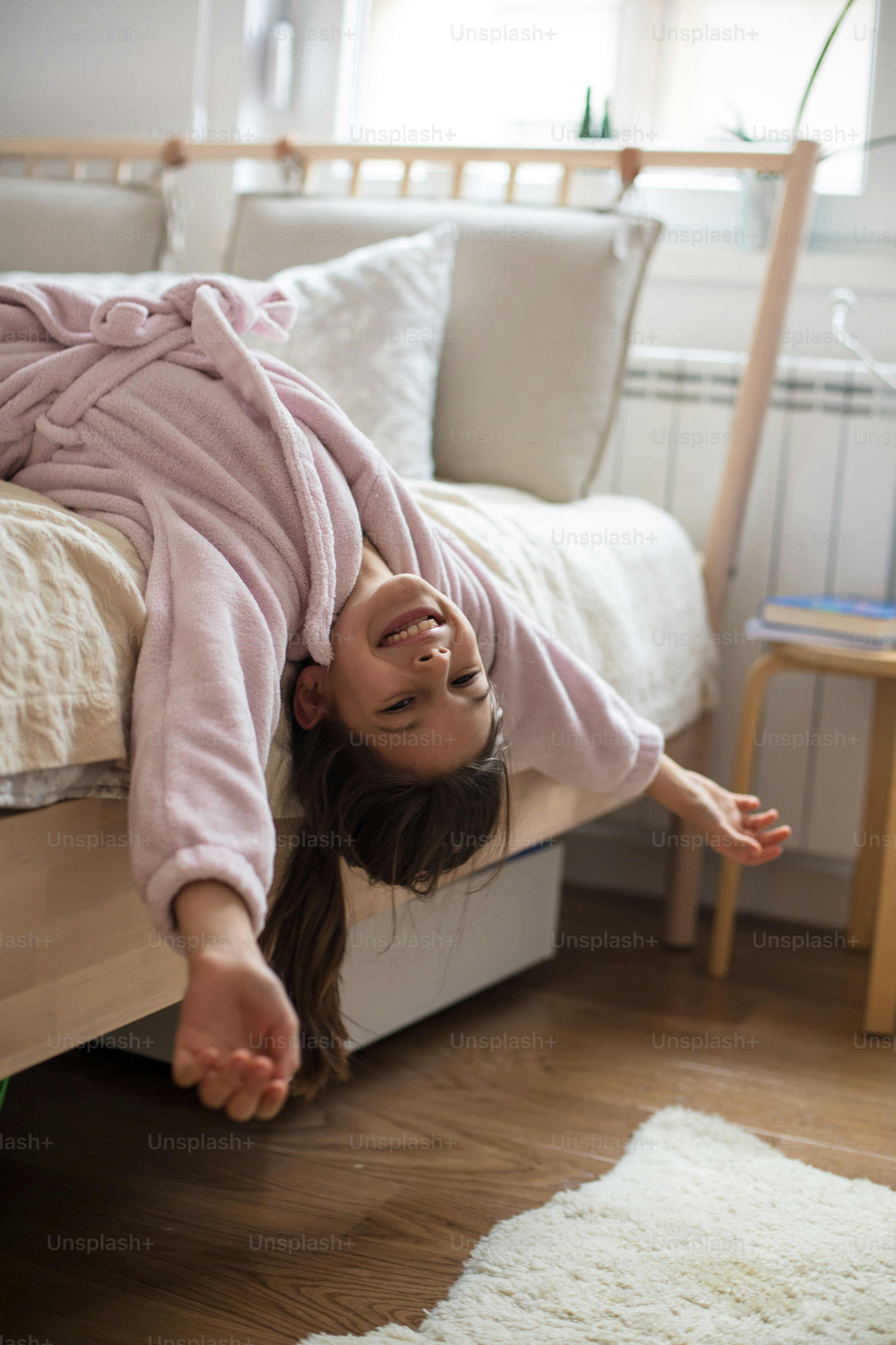 Petite fille heureuse sur son lit en peignoir.