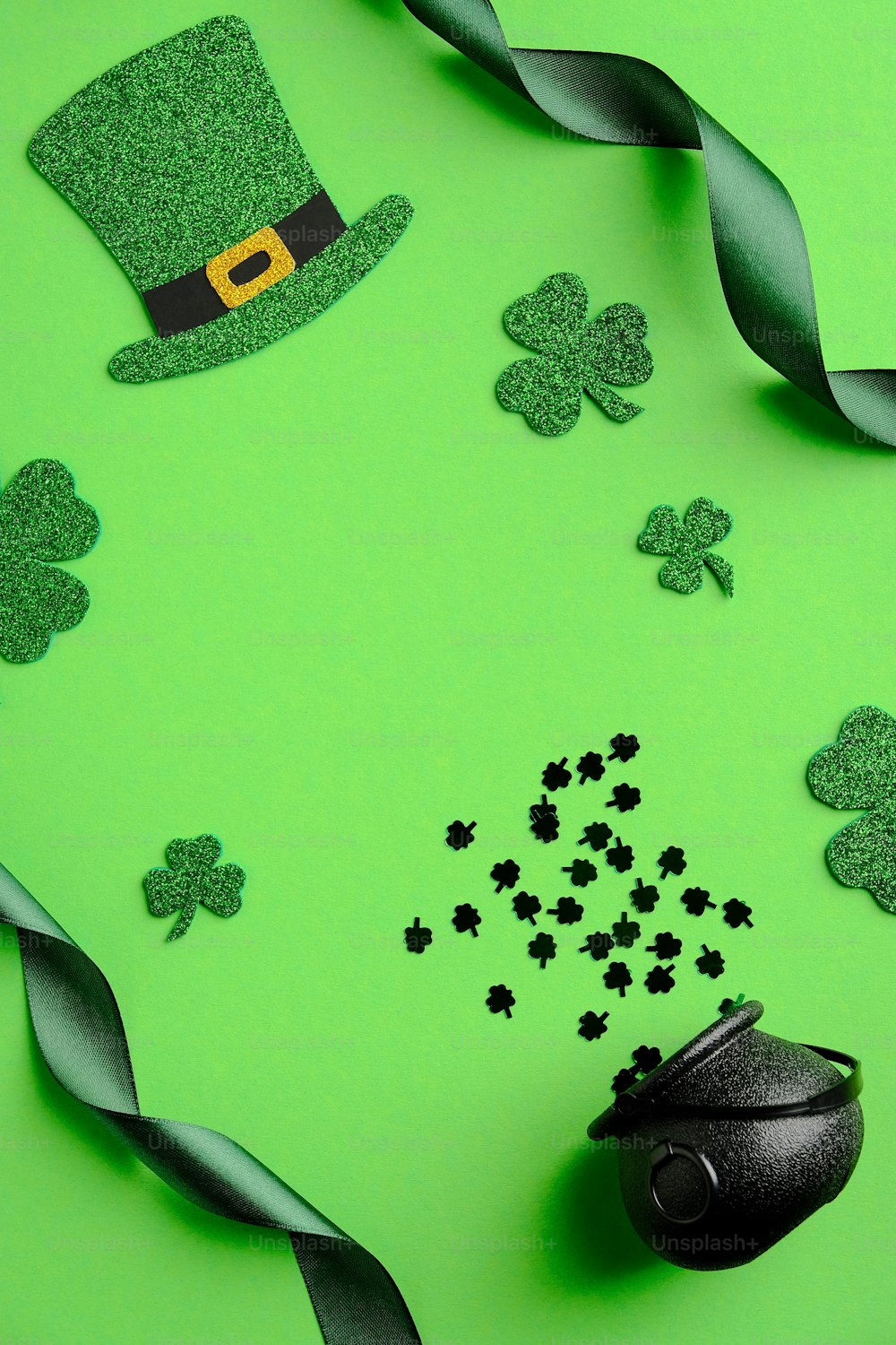 Composition de la Saint-Patrick. Fond vert de la Saint-Patrick avec chapeau de lutin, feuilles de trèfle, pot d’or, ruban. Vue de dessus, au-dessus de la tête.