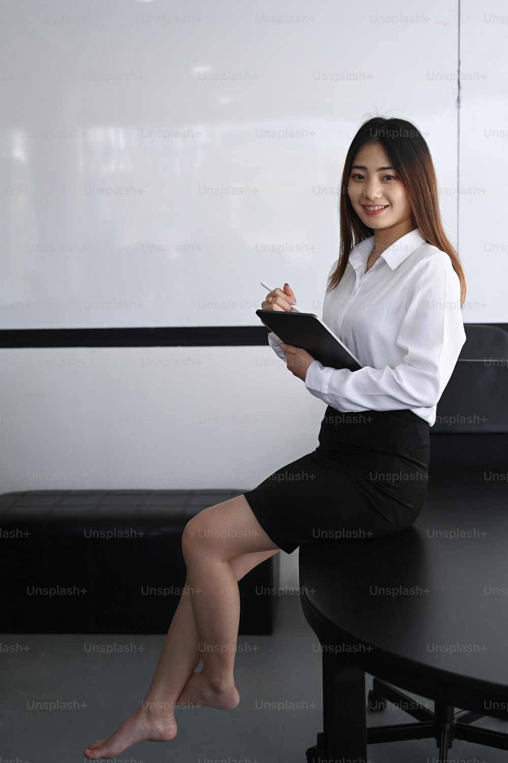 Portrait of confident young woman office worker holding folder sitting on table in meeting room.