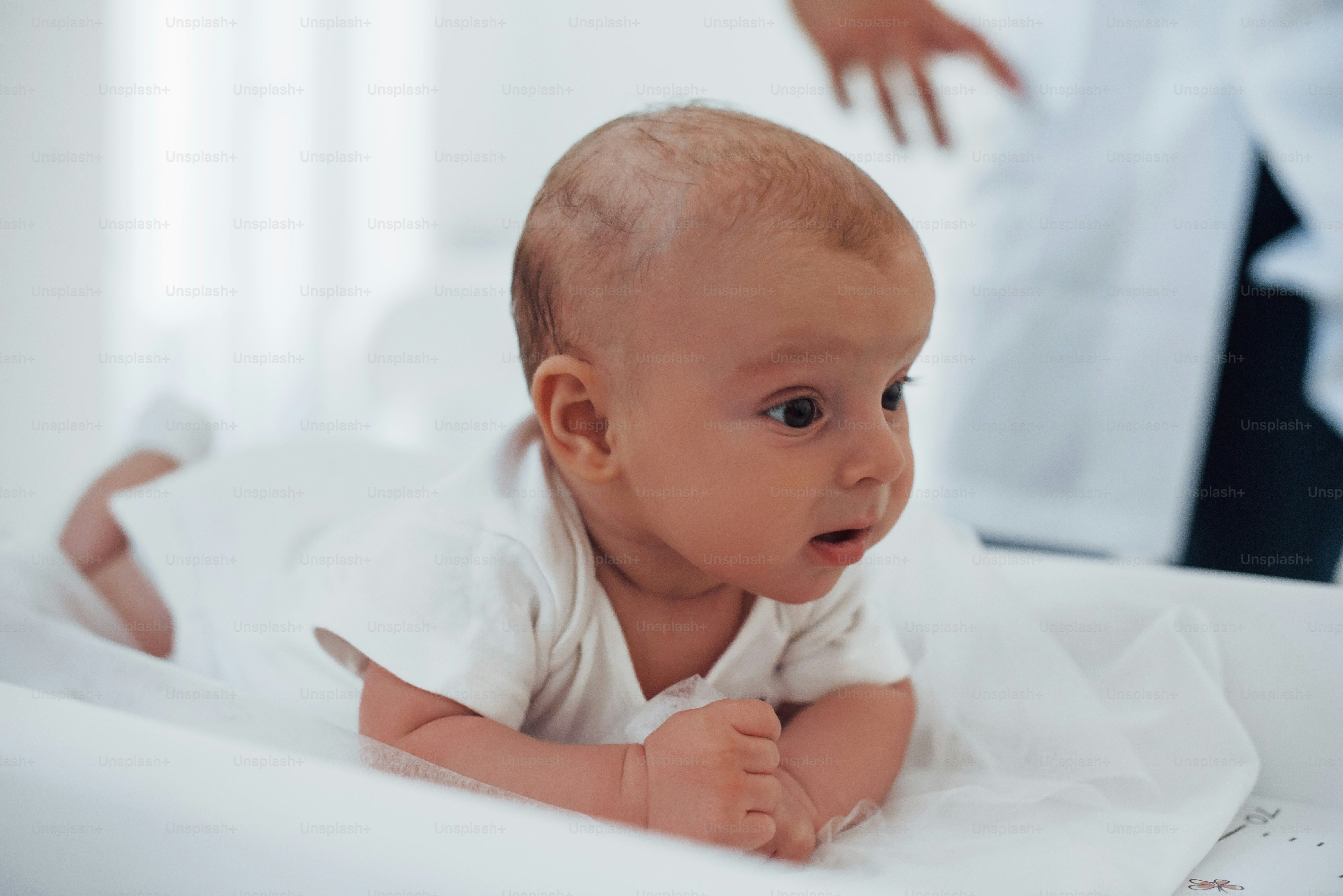 Little baby lying on the table. Young pediatrician is in the clinic at daytime.