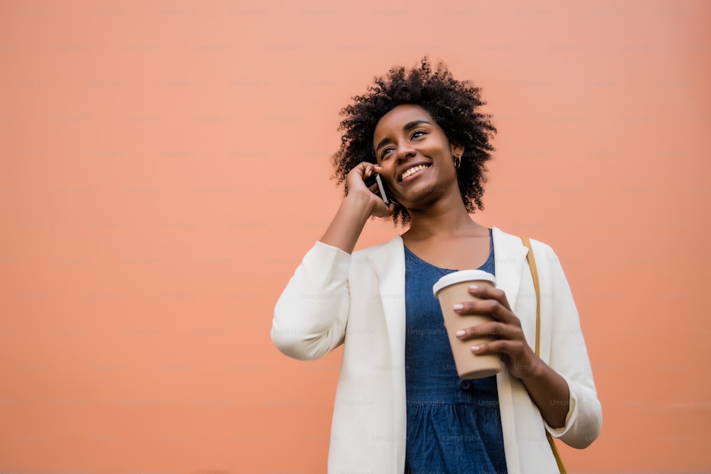 Ritratto di donna d'affari afro che parla al telefono mentre si trova all'aperto in strada. Concetto di business e urbano.