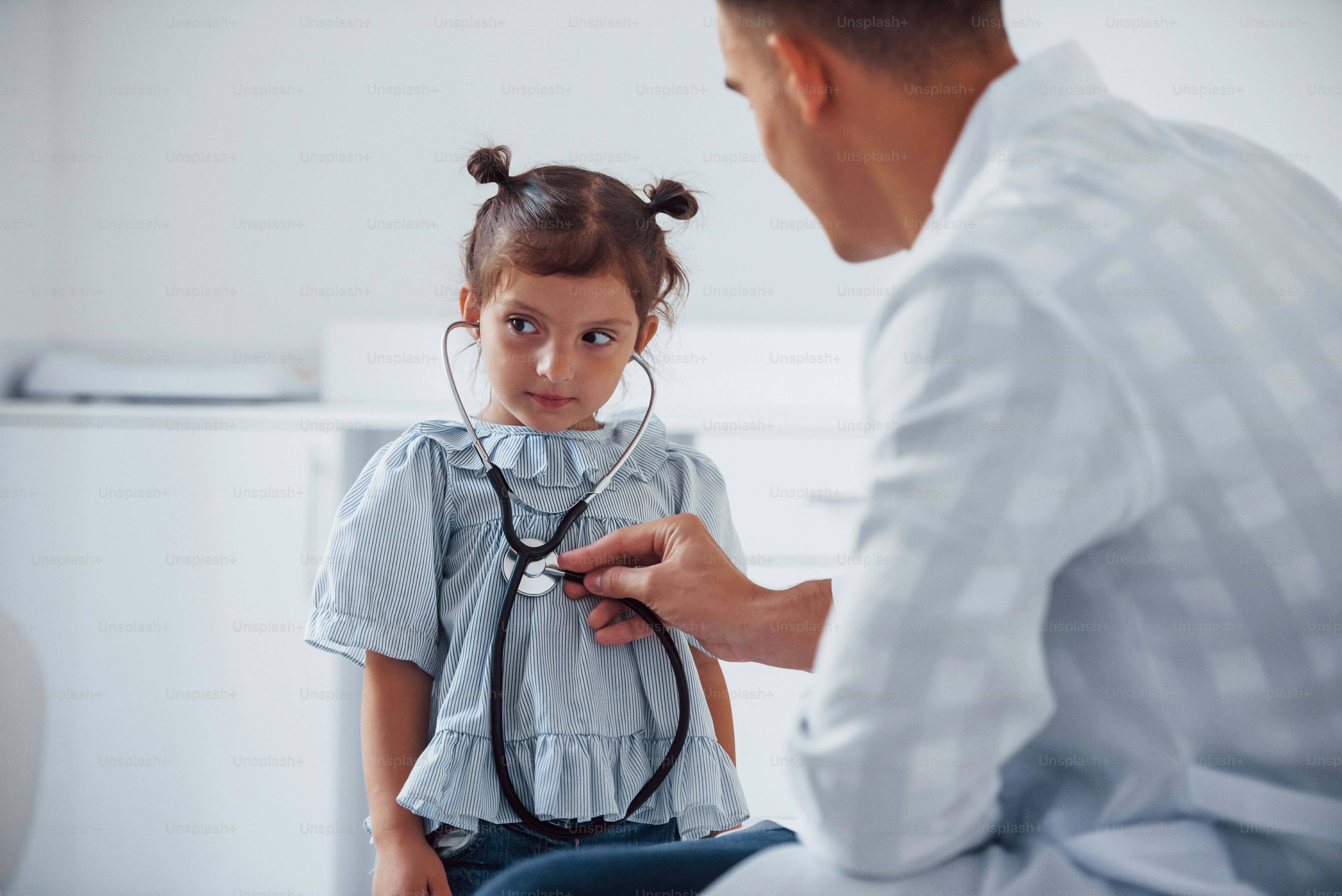 Junge Kinderärztin arbeitet mit kleinen weiblichen Besuchern in der Klinik.