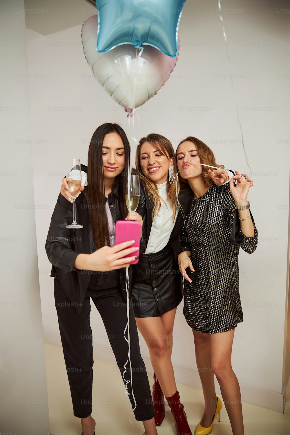 Jeune femme caucasienne aux cheveux noirs et ses amis espiègles prenant des selfies avec un téléphone portable à la maison