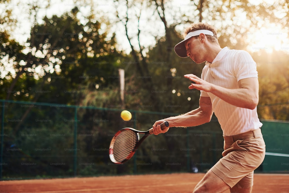 Photo in motion. Young tennis player in sportive clothes is on the court outdoors.