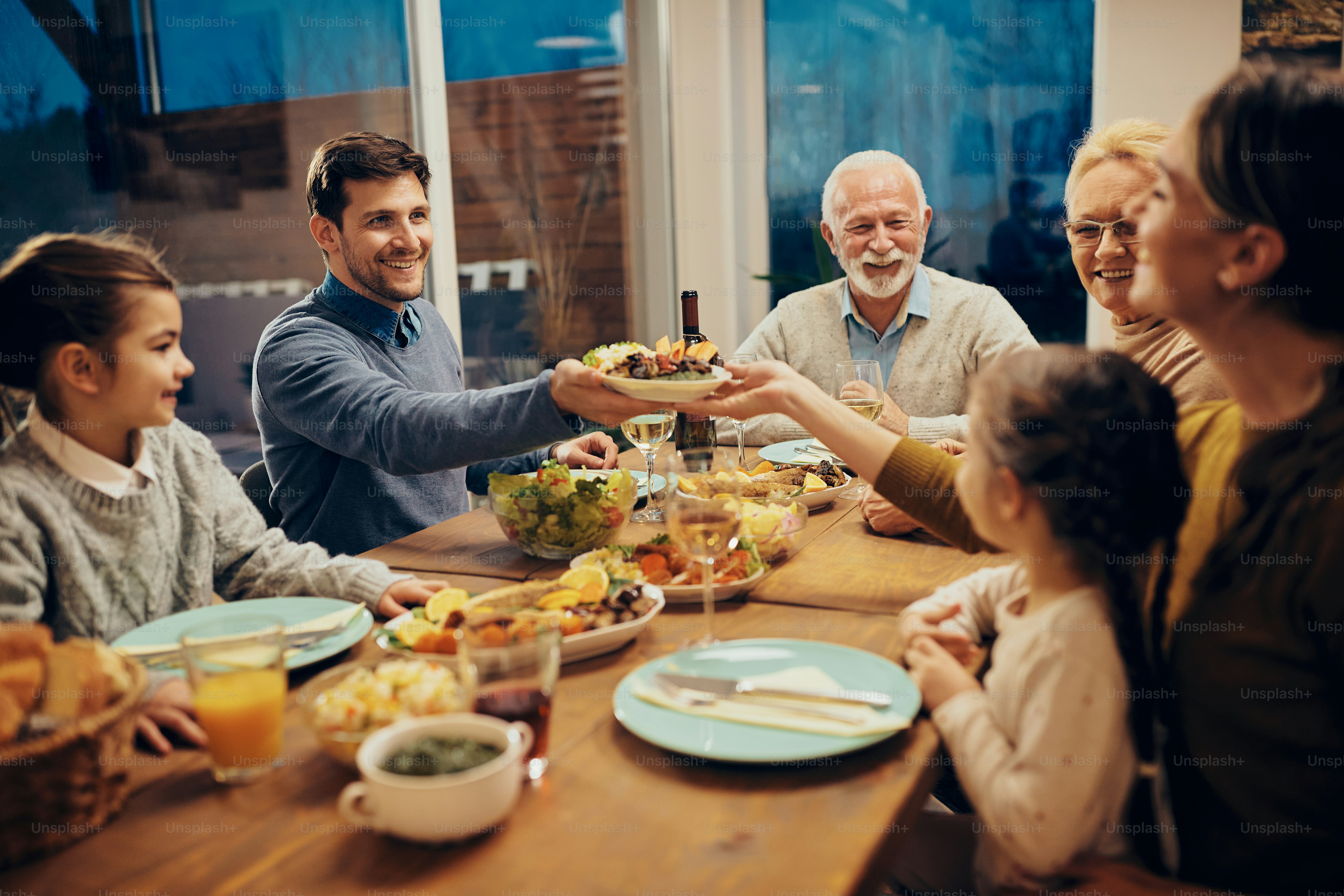 Pareja feliz pasando comida mientras almuerza en familia en el comedor