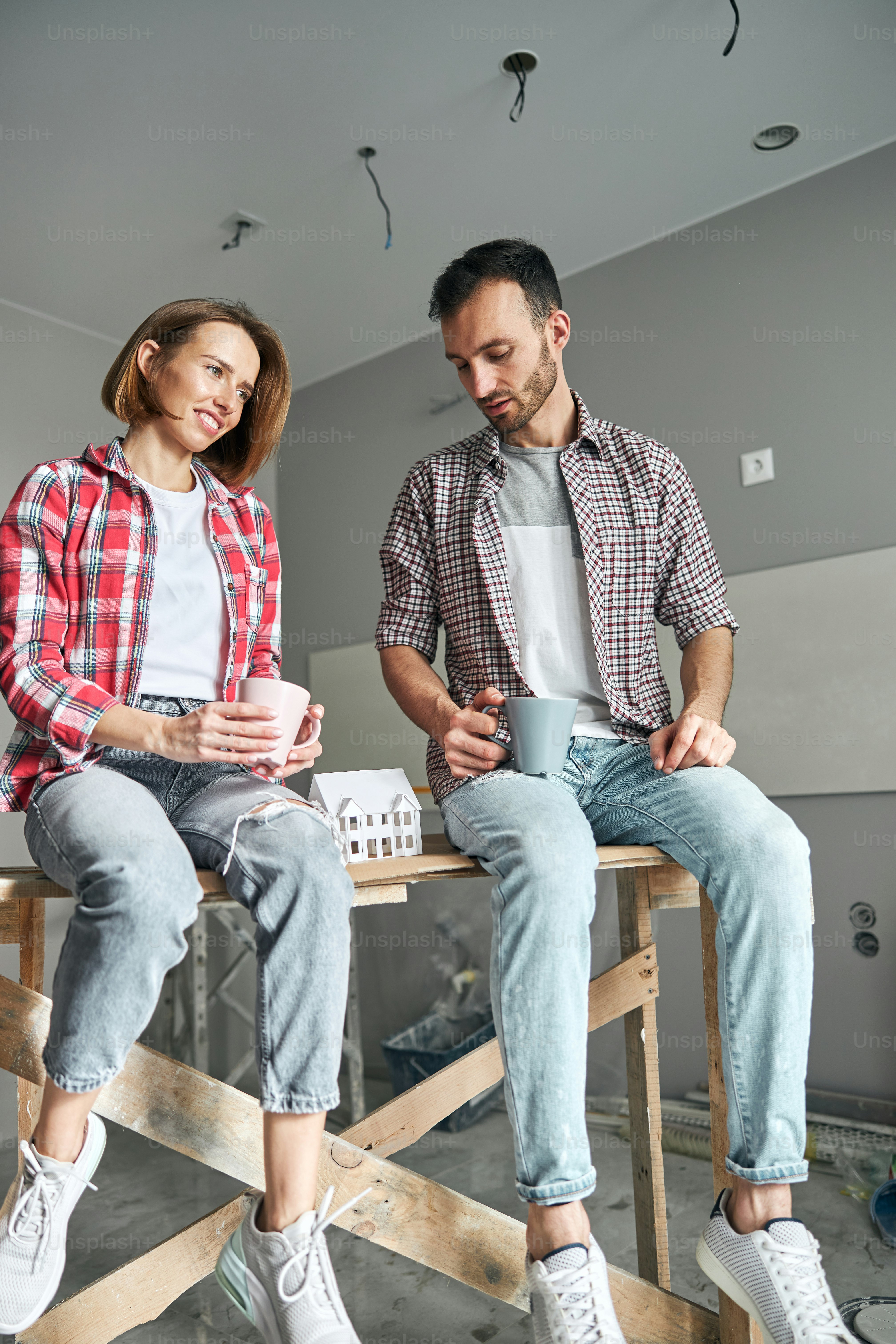Femme rêveuse satisfaite et un homme endormi assis sur une table en bois pendant la pause-café