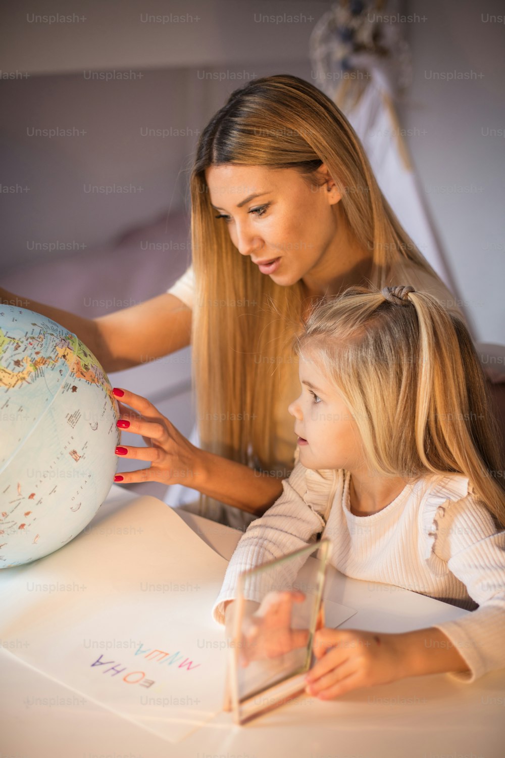 Madre e figlia che imparano la geografia su un globo mondiale.