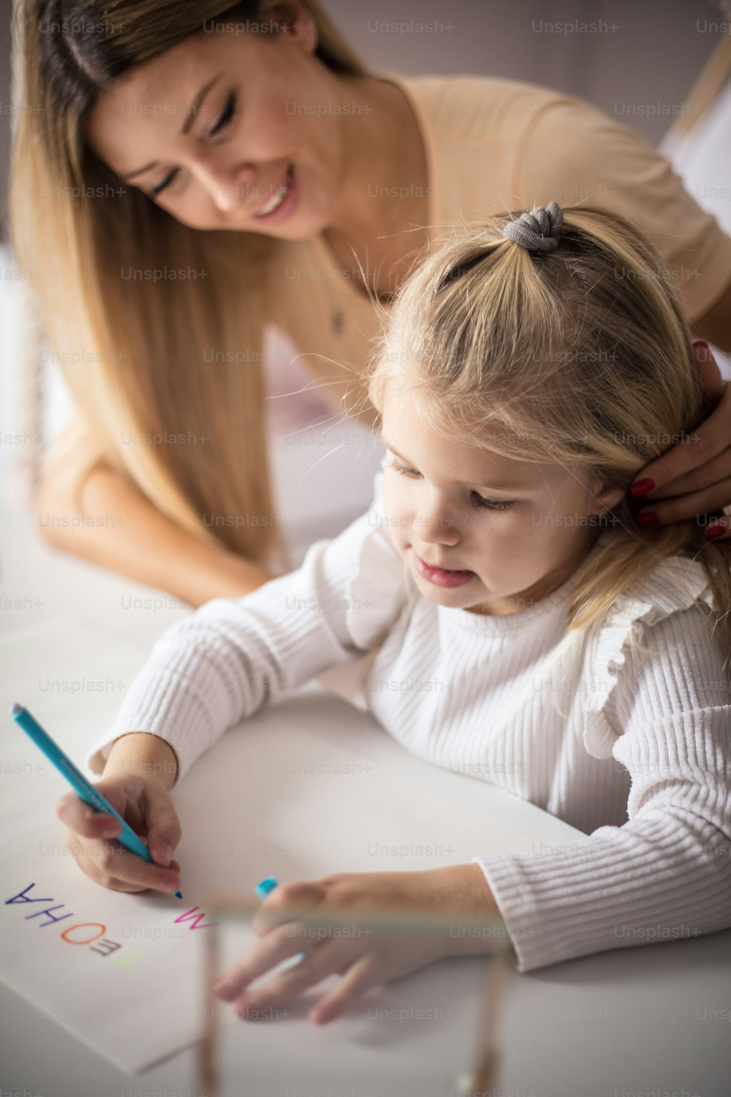 Mother and daughter in bedroom. Little girl drawing.