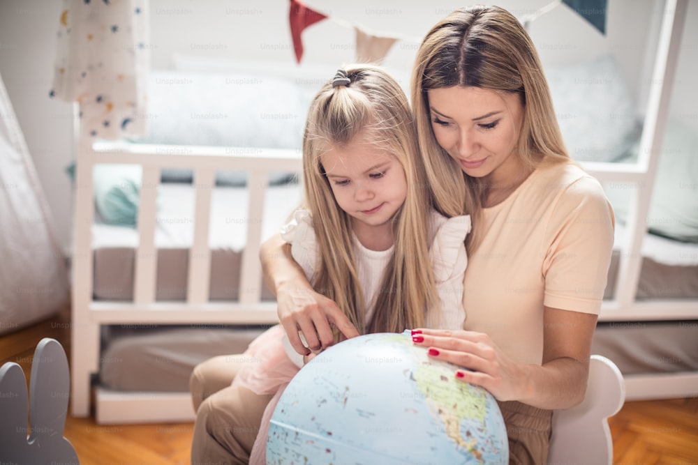 Mother and daughter learning geography on a world globe