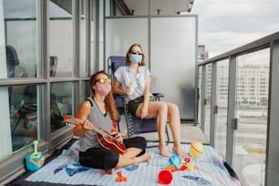 Young lesbian lgbtq women family spending time together on balcony at home. Staycation during coronavirus covid-19 pandemic in the world. Preventive measures against virus spread.