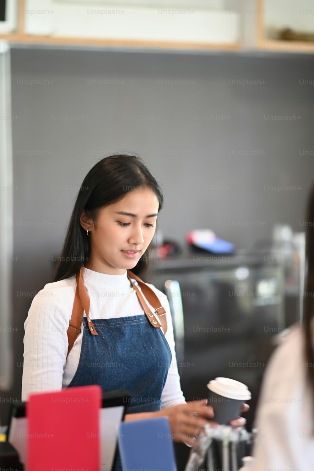 Cheerful barista giving paper cups of coffee to customer at counter bar.