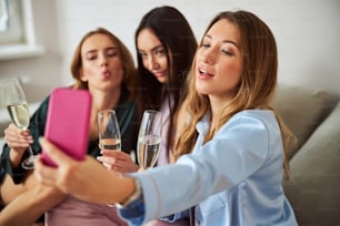 Closeup portrait of a pretty blonde lady taking pictures of herself and her female friends