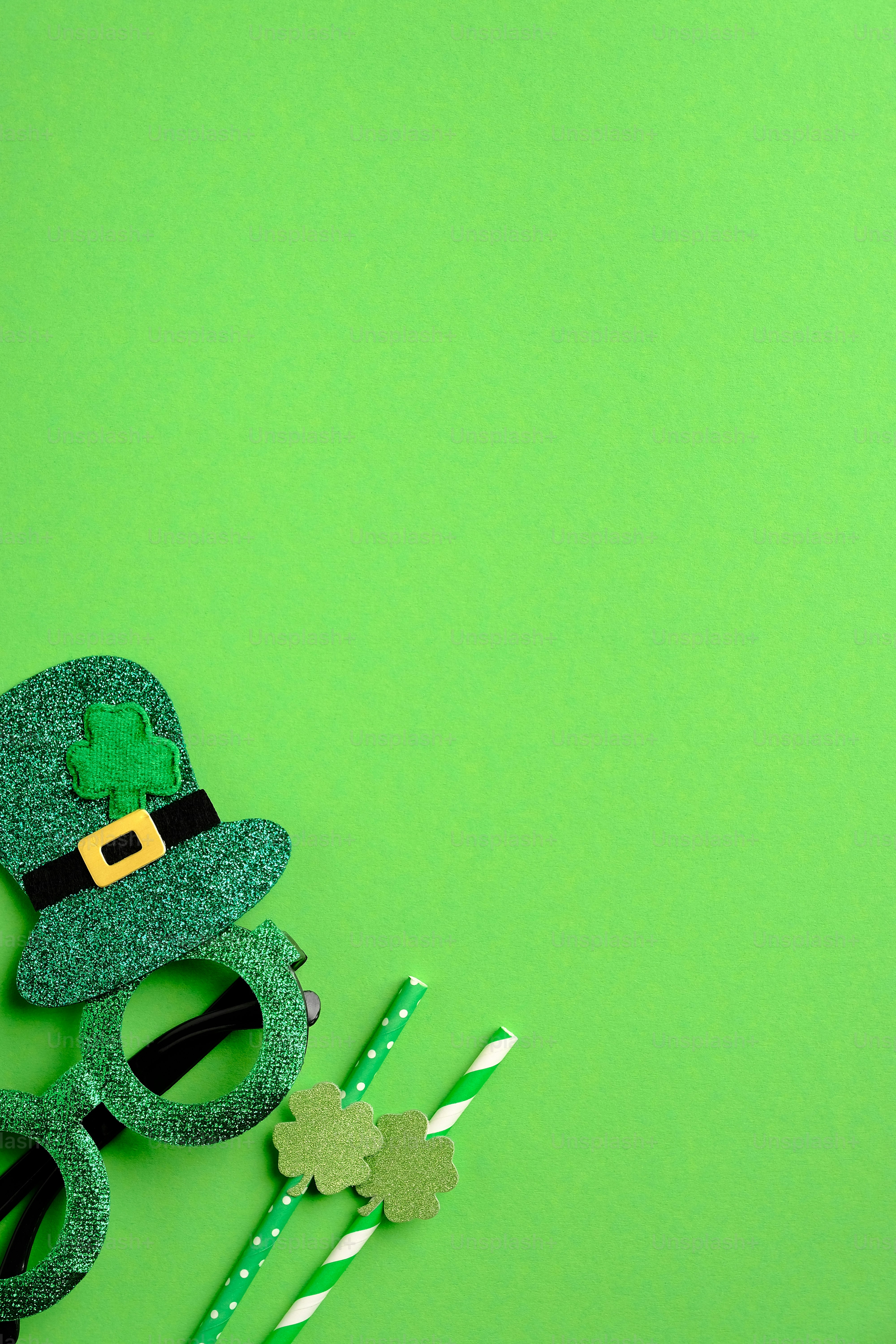 Saint Patricks day minimal concept. Patricks day glasses and drinking straws on green background. St Patricks day party invitation design. Flat lay, top view.