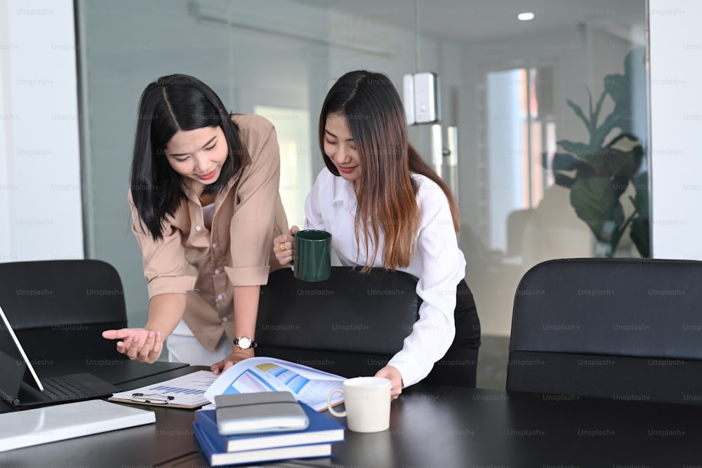 Two young businesswoman reading and analyzing report in office.