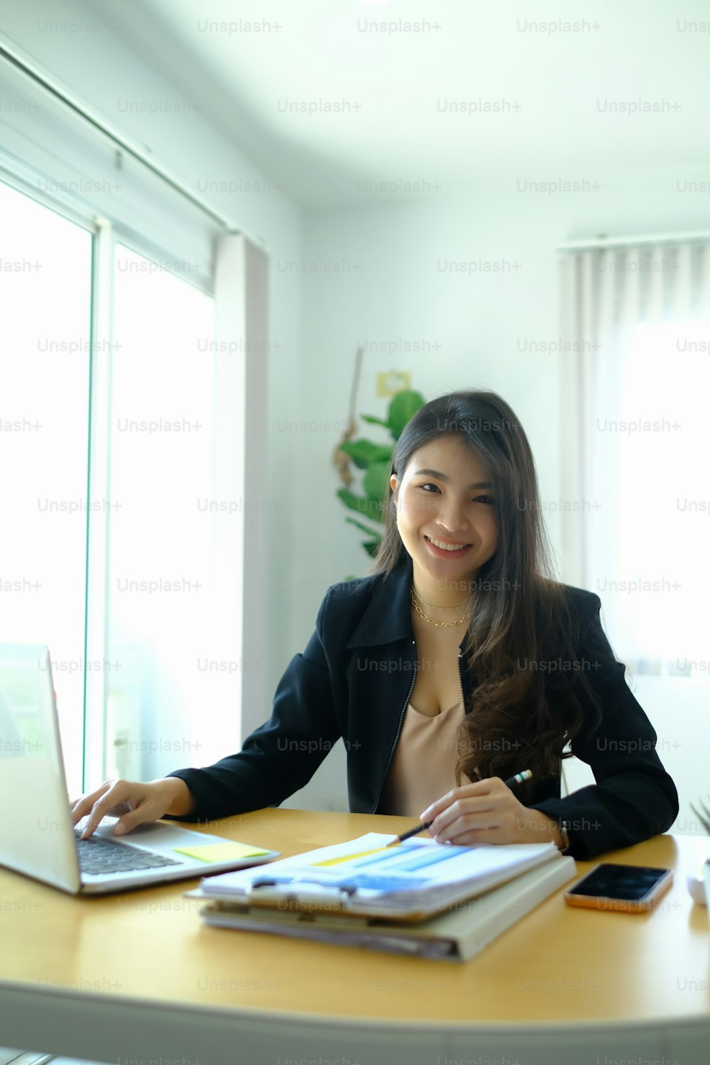 Ritratto di allegra donna d'affari in giacca e cravatta che lavora con il computer alla scrivania dell'ufficio e sorride alla macchina fotografica.