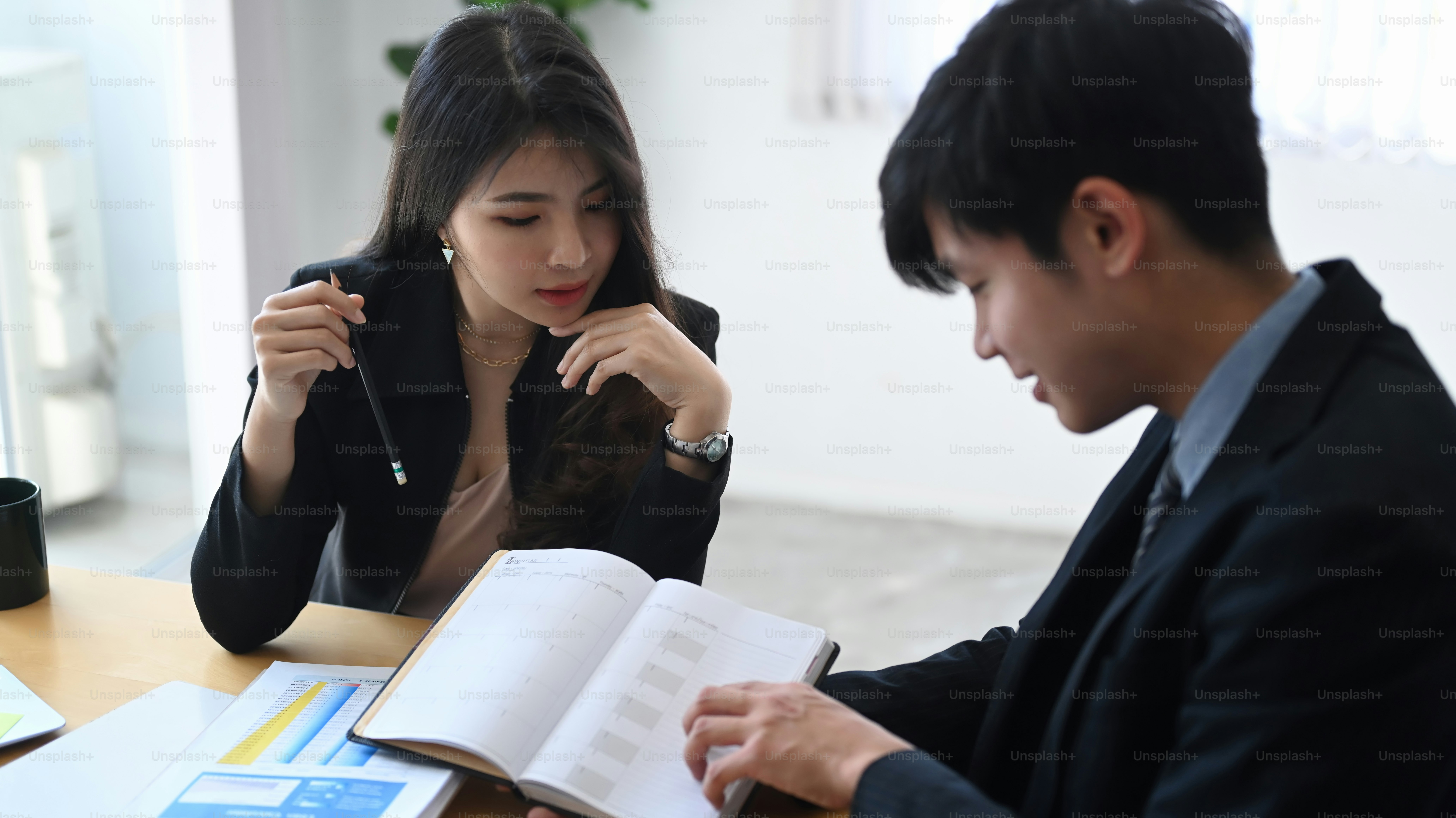 Two successful business people discussing company financial strategy in meeting room.