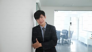 Portrait of attractive businessman standing with arms crossed at office doorway.