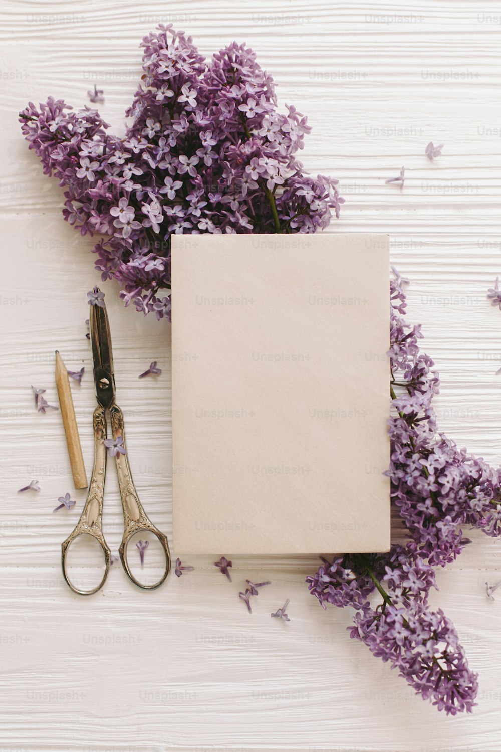 Happy mothers day. Stylish card on beautiful lilac flowers and vintage scissors, pencil on white rustic wood, top view. Happy womens day. Floral greeting card template, space for text