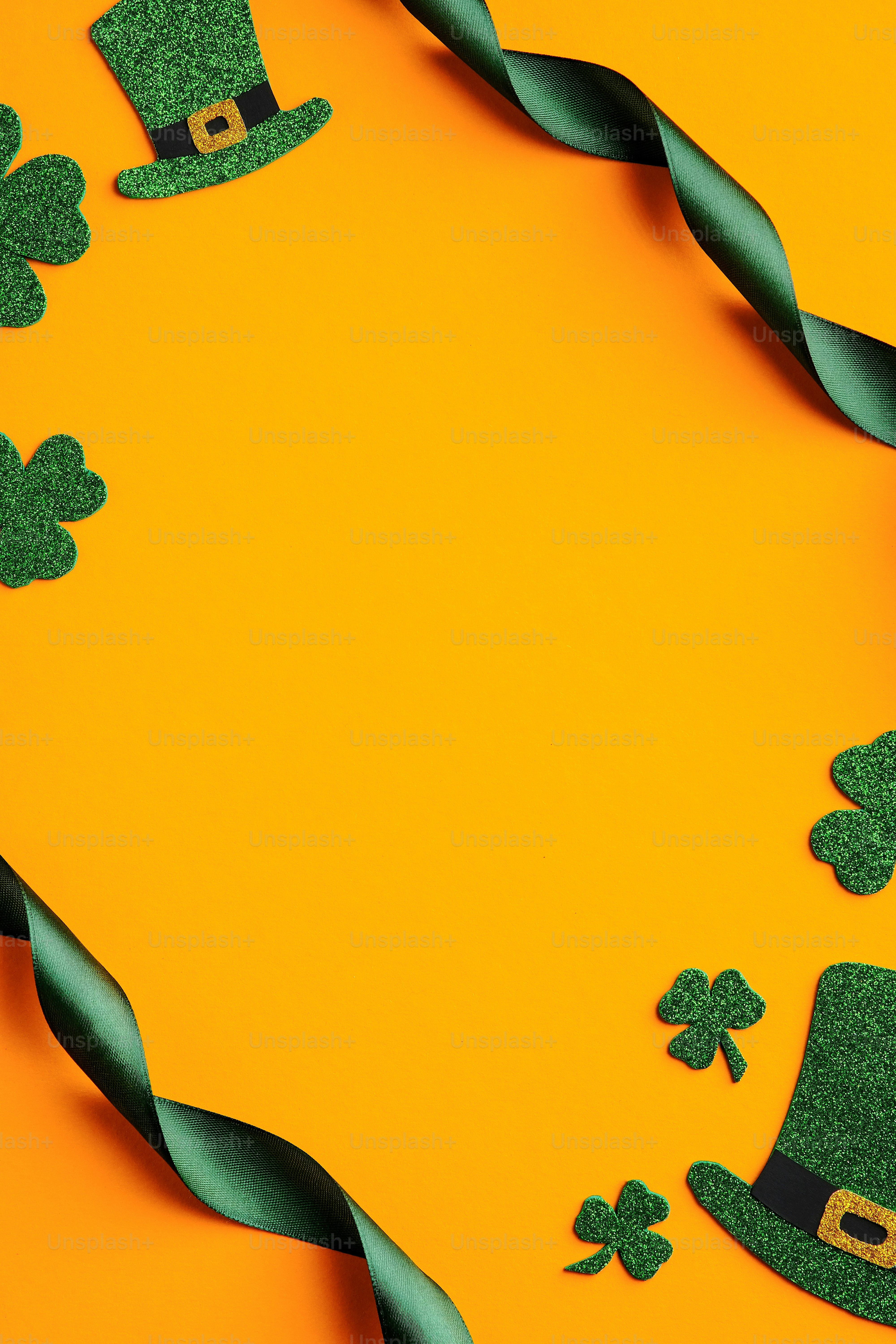 St Patrick's Day banner design. Frame made of green ribbon, Irish elf hats, shamrock leaves on orange background. Happy Saint Patricks Day concept
