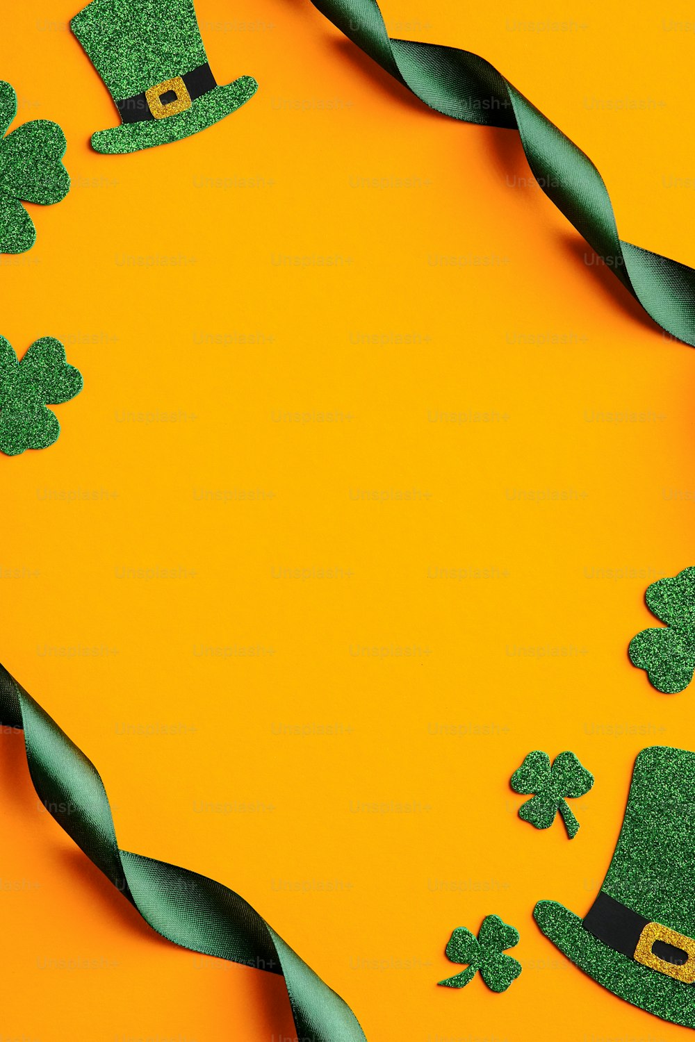 St. Patrick's Day Banner Design. Gestell aus grünem Band, irische Elfenhüte, Kleeblattblätter auf orangefarbenem Hintergrund. Happy Saint Patricks Day Konzept