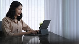 Smiling young woman office worker working with computer tablet while sitting in calm office room.