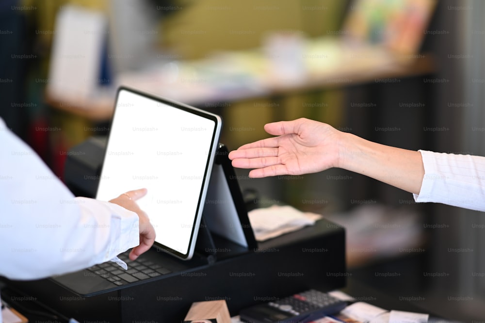 Cameriera che utilizza il tablet per ricevere gli ordini dai clienti al servizio del bancone nella caffetteria.