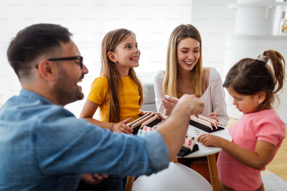 Happy parents and children having fun, playing board game at home