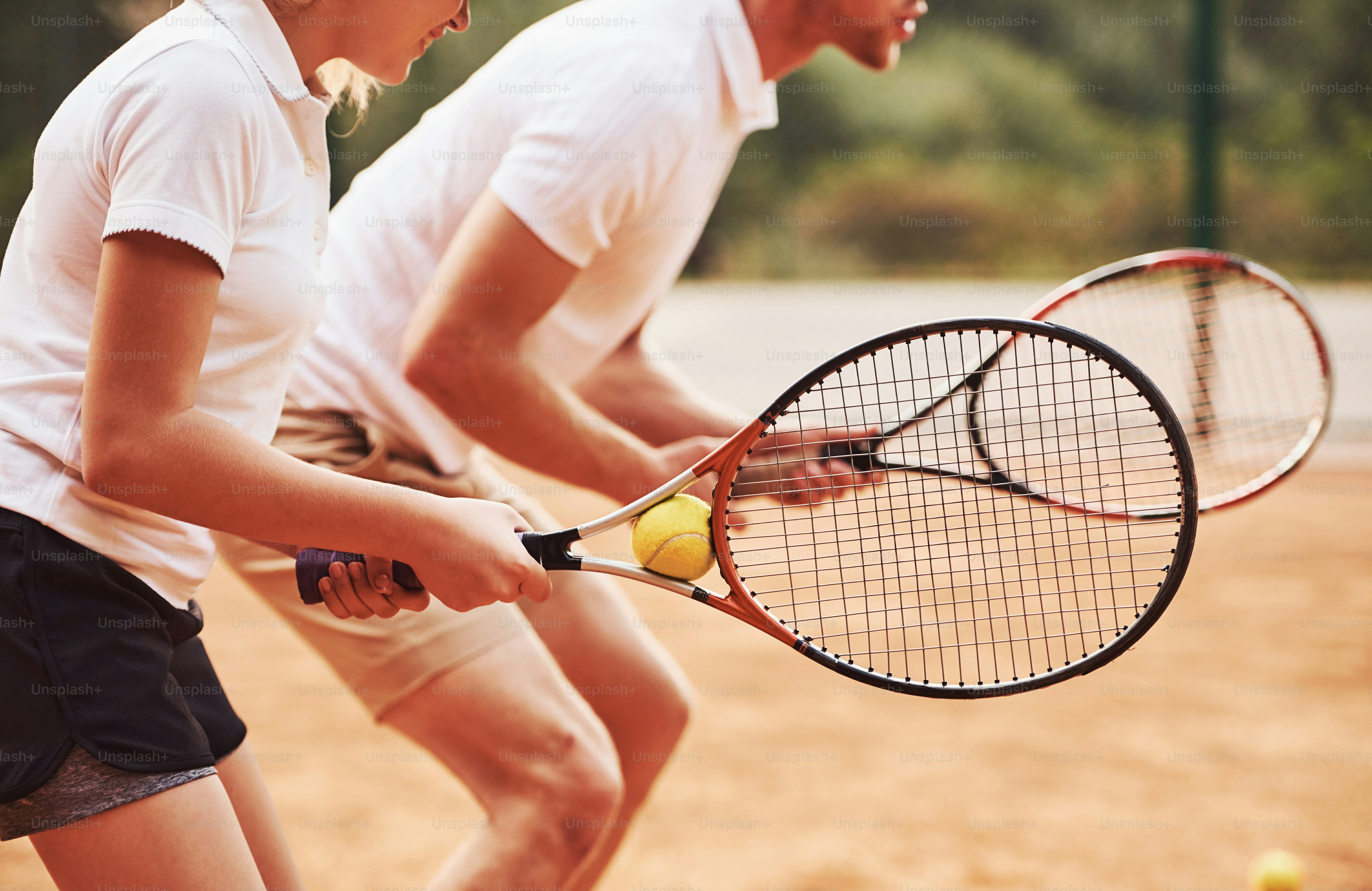 Side view. Coach teaching female student tennis game in the court outdoors.
