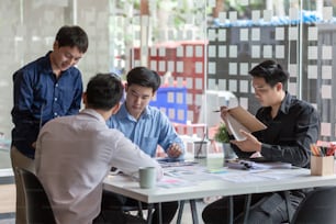 Gruppo di giovani uomini d'affari asiatici che lavorano e fanno brainstorming e scambiano idee durante l'incontro.