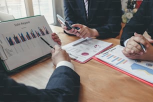 Gli uomini d'affari parlano di investimenti, pianificazione del marketing e visualizzano la scheda tecnica nel grafico dei dati finanziari.