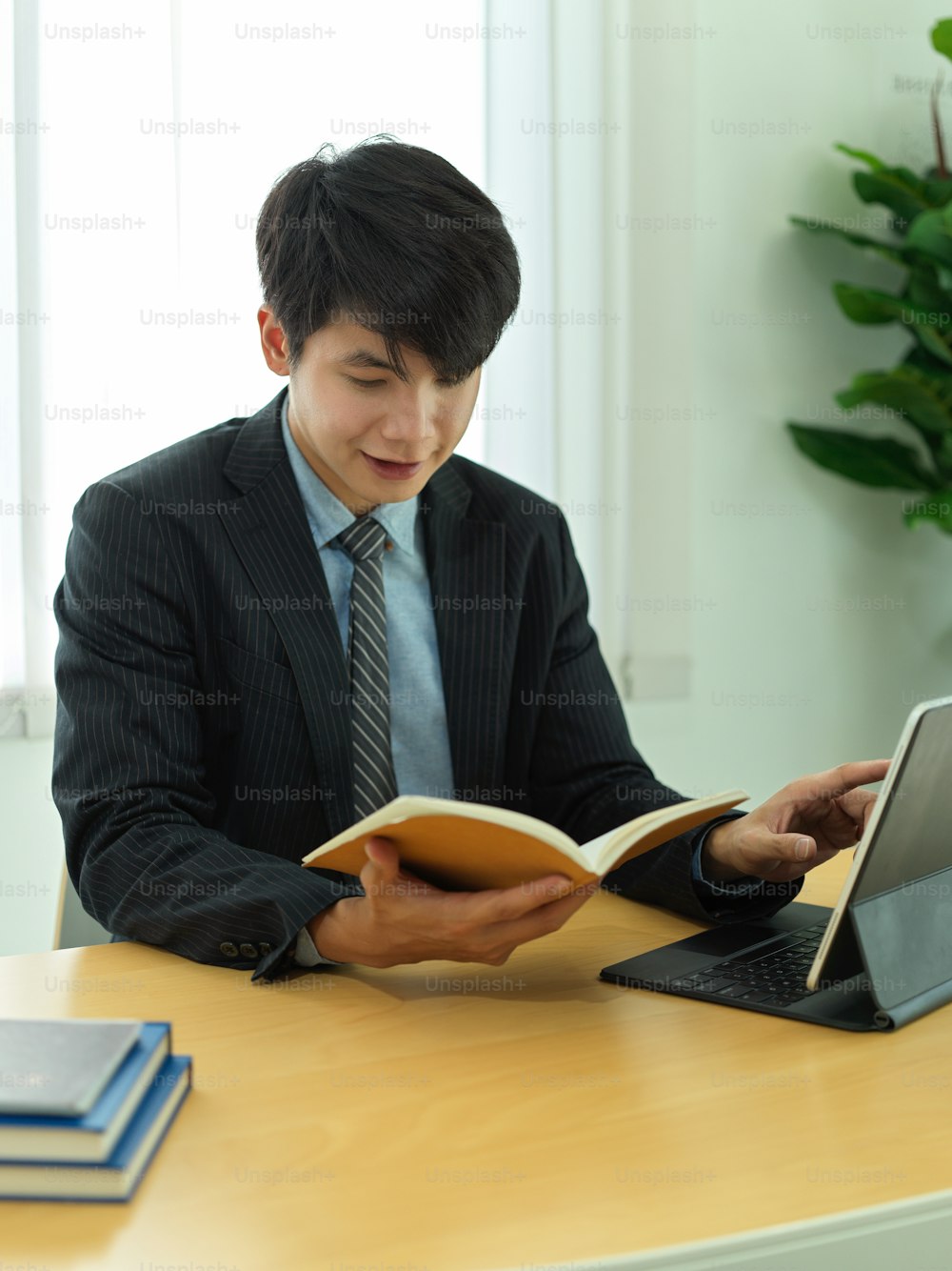 Portrait of businessman reading informations on his schedule book while working with digital tablet