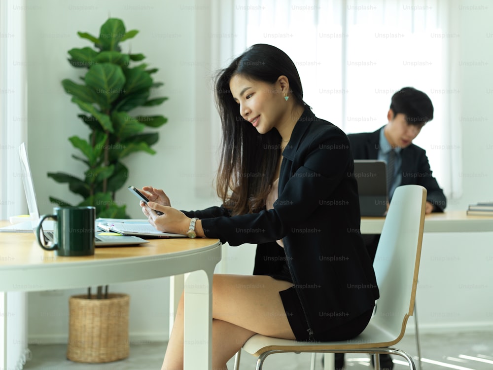 Portrait of businesswoman using smartphone while relaxing from work at workplace