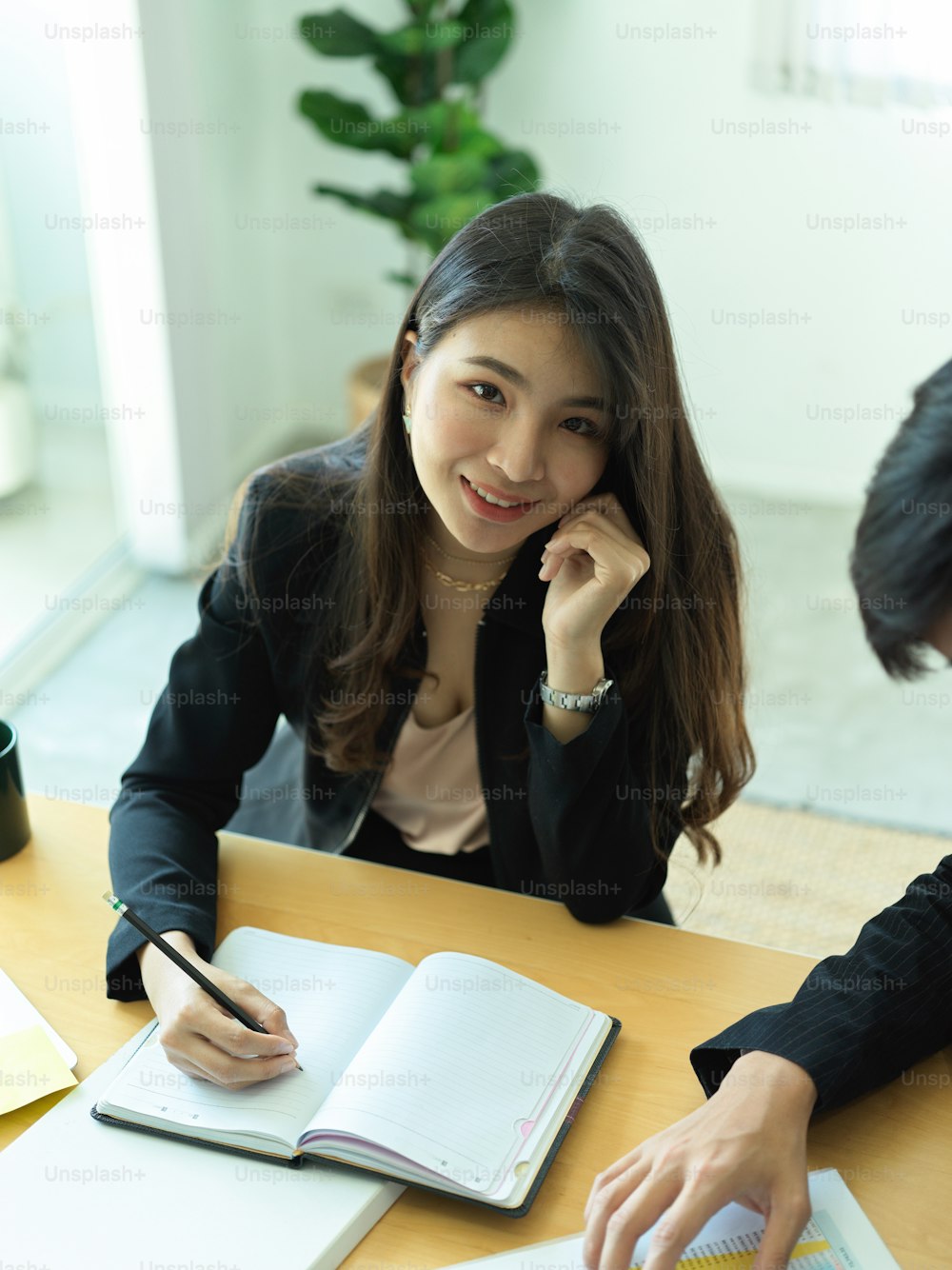Portrait of businesswoman smiling to camera while consulting on her work with her coworker in office room