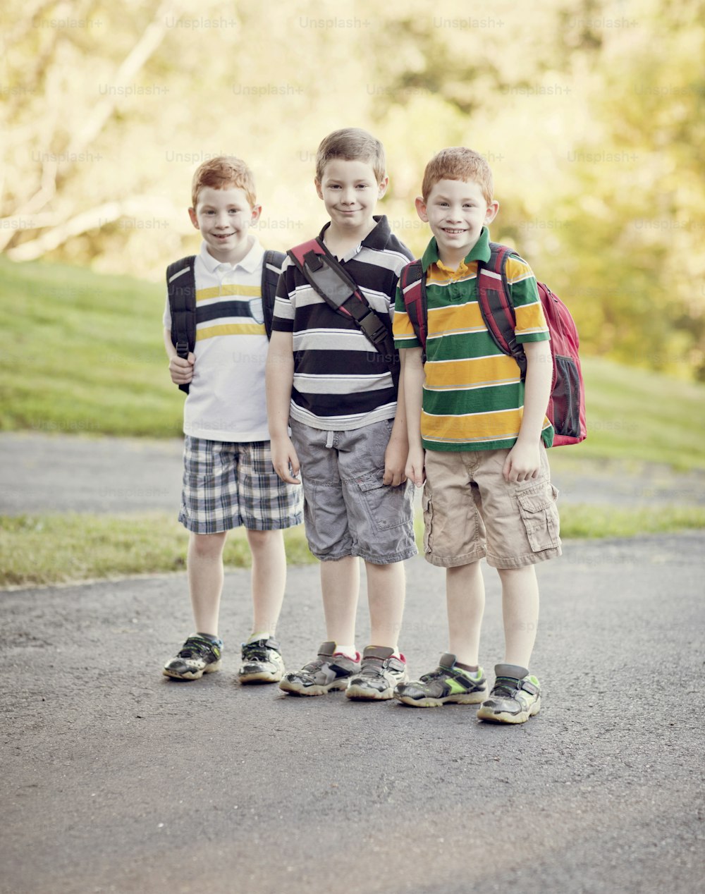 Three young boys standing outside with backpacks with retro filter