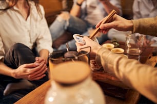 Primo piano di mani maschili che preparano una deliziosa tisana mentre i clienti si siedono al tavolo di legno