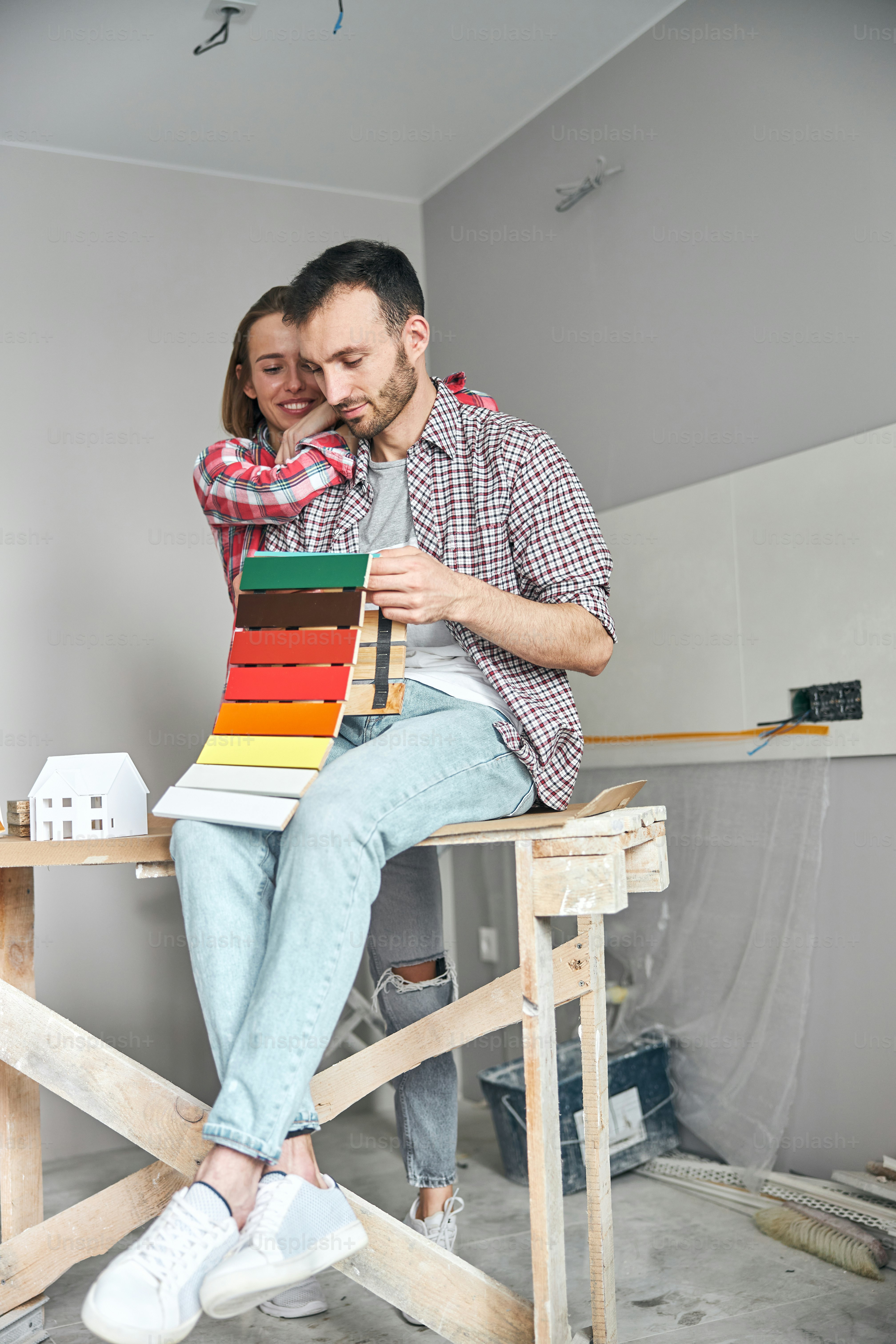 Heureuse jeune belle dame blonde scrutant le kit d’échantillons de panneaux de fibres colorés dans les mains de son mari
