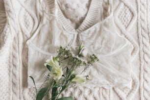 Stylish lace lingerie and spring flowers on cozy beige sweater. Soft trendy feminine image. Happy Women's day. Woman essentials, fragrance
