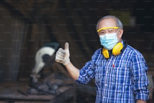 A mature carpenter standing confidently in his workshop