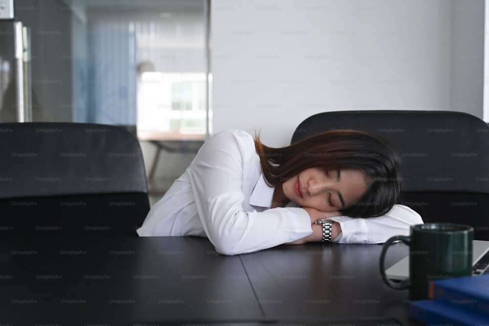 Young woman office worker tired from working and take a nap from depressed work on office desk.