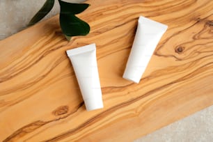 Set of white plastic tubes with moisturizer cream on wooden board. Beauty and spa concept.