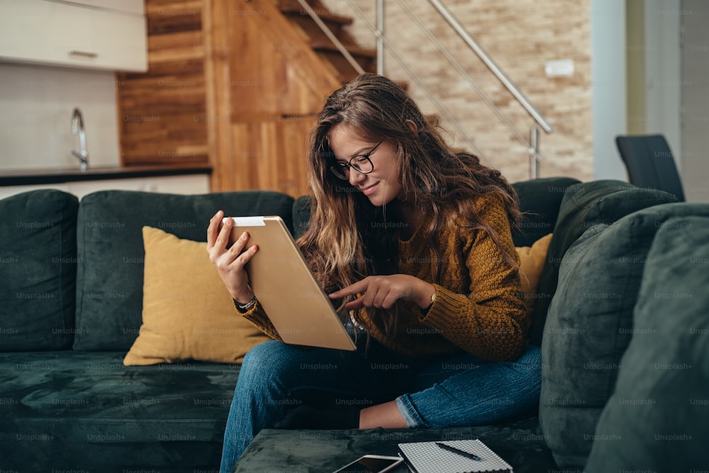 Foto de una mujer joven usando una tableta digital mientras trabaja desde casa
