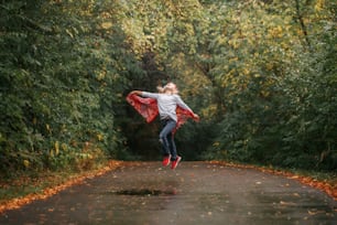 Preschool girl playing in autumn fall park. Freedom of creativity and imagination inspiration. Child running jumping outside in street road. Happy childhood lifestyle. Outdoor activity for kids.