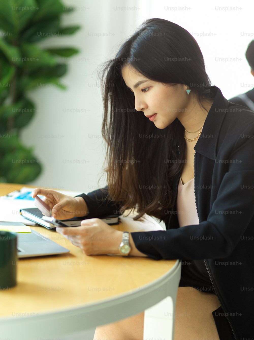 Cropped shot of businesswoman online paying with smartphone and credit card in office room