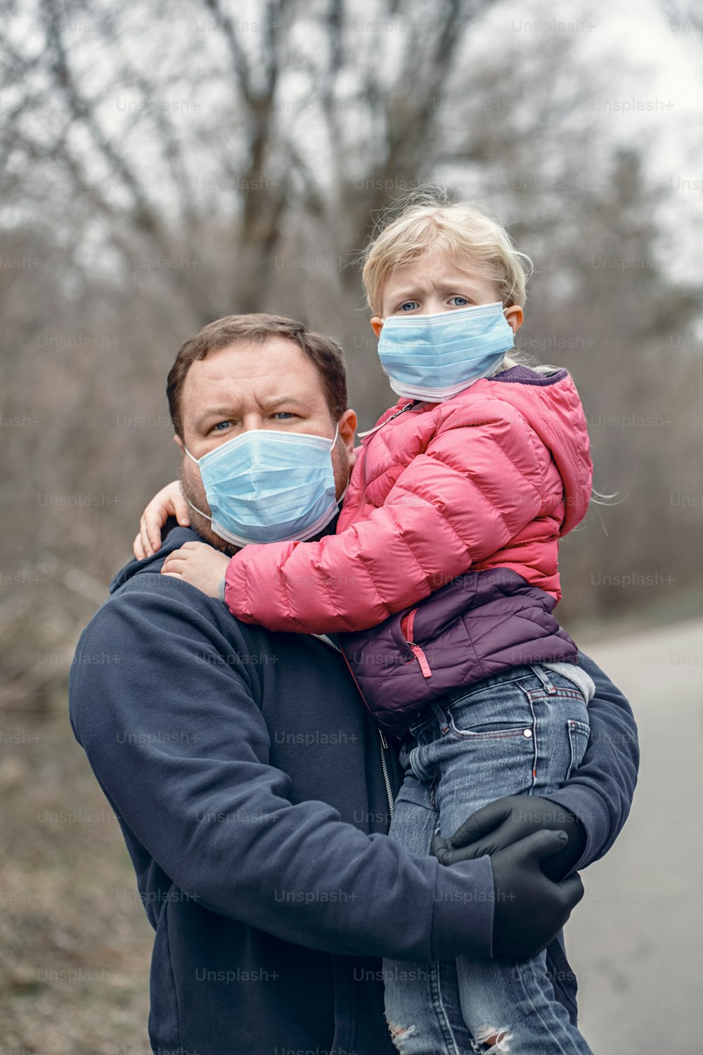 Padre caucasico con bambina bambina che indossa maschere facciali sanitarie all'aperto. Padre e figlia in famiglia si proteggono dalla pericolosa diffusione del virus. Quarantena COVID-19 da Coronavirus.
